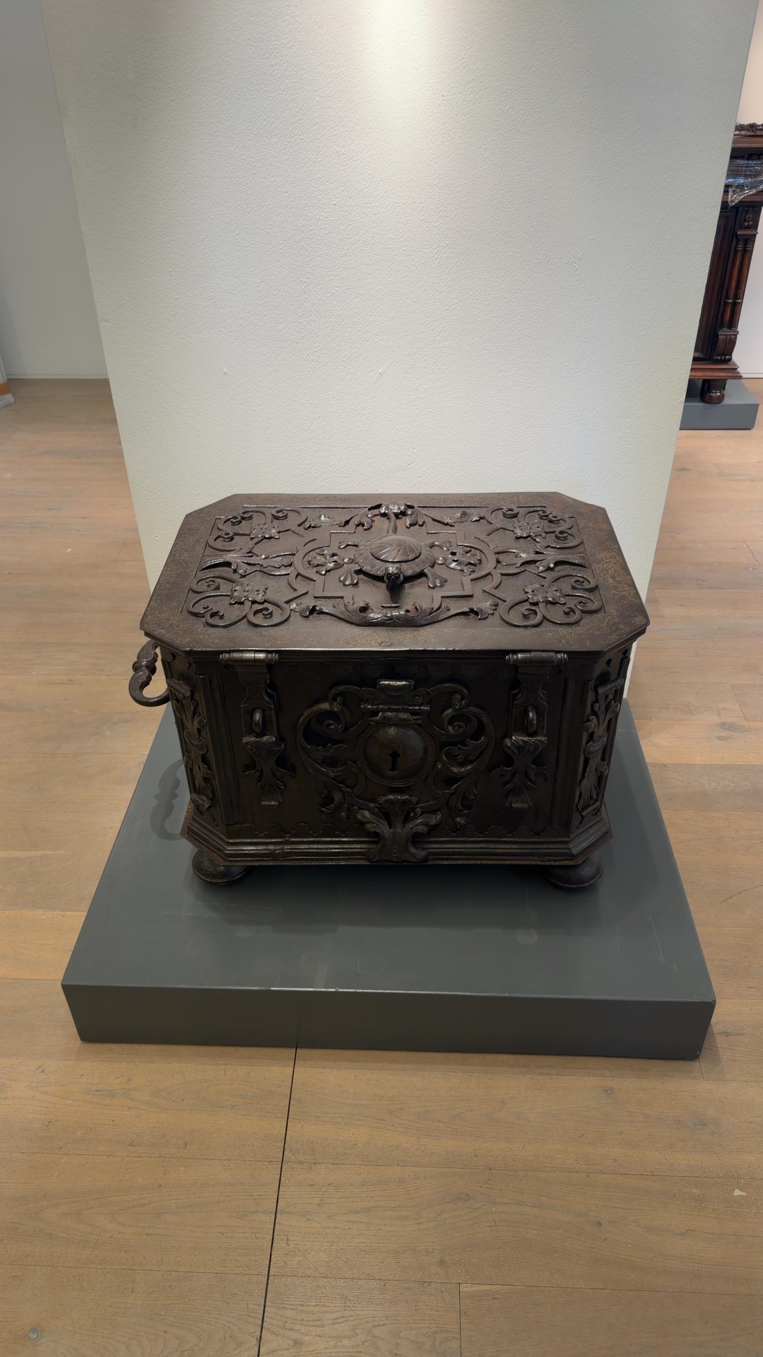 Early 18th century German wrought iron strongbox decorated with ornate scrollwork and a sculpted turtle on the lid, resting on a museum plinth - view 1