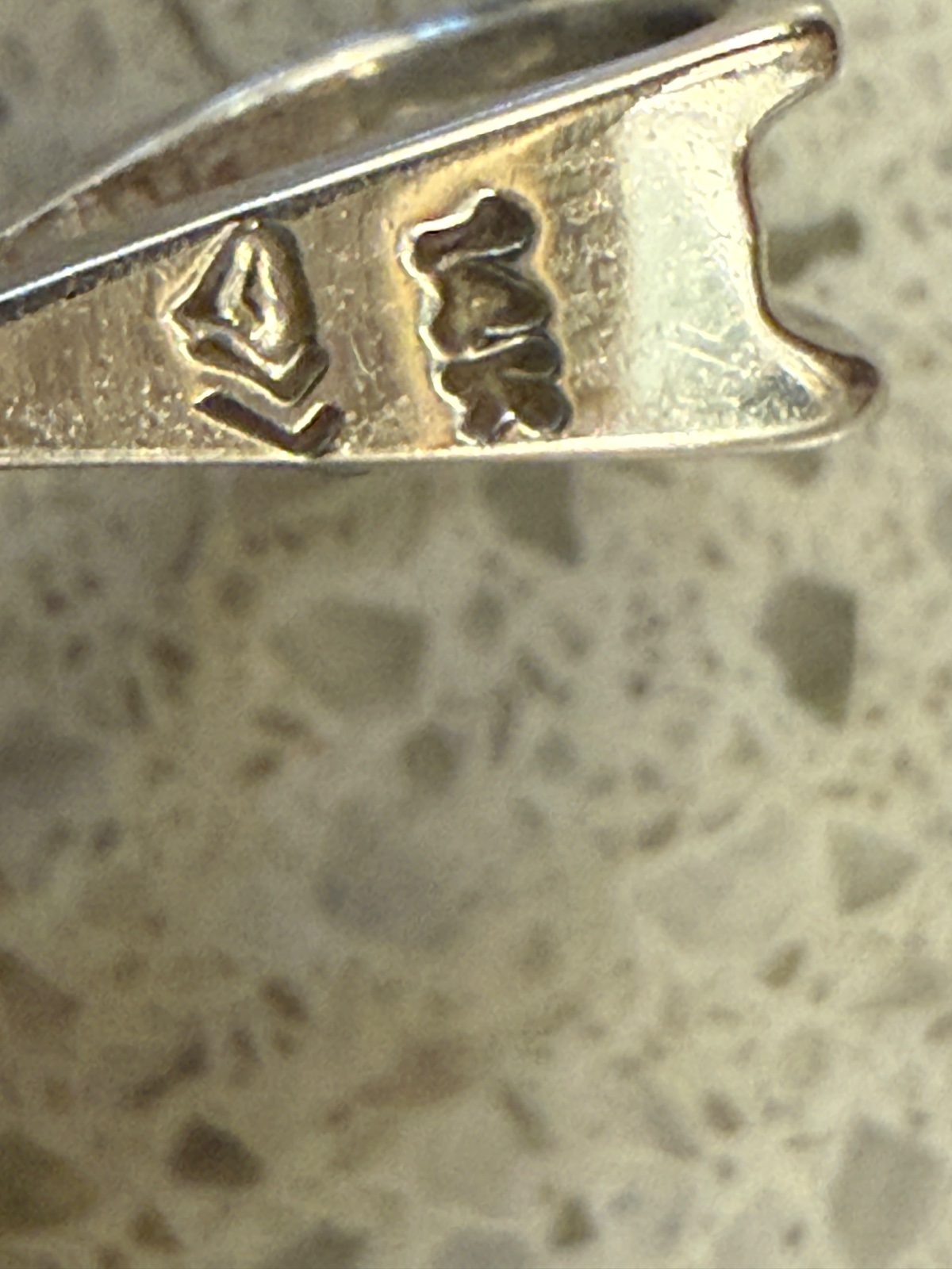 Macro photograph of a 14-karat gold pendant bail showing a '14K' purity stamp and a geometric maker's mark. - view 1