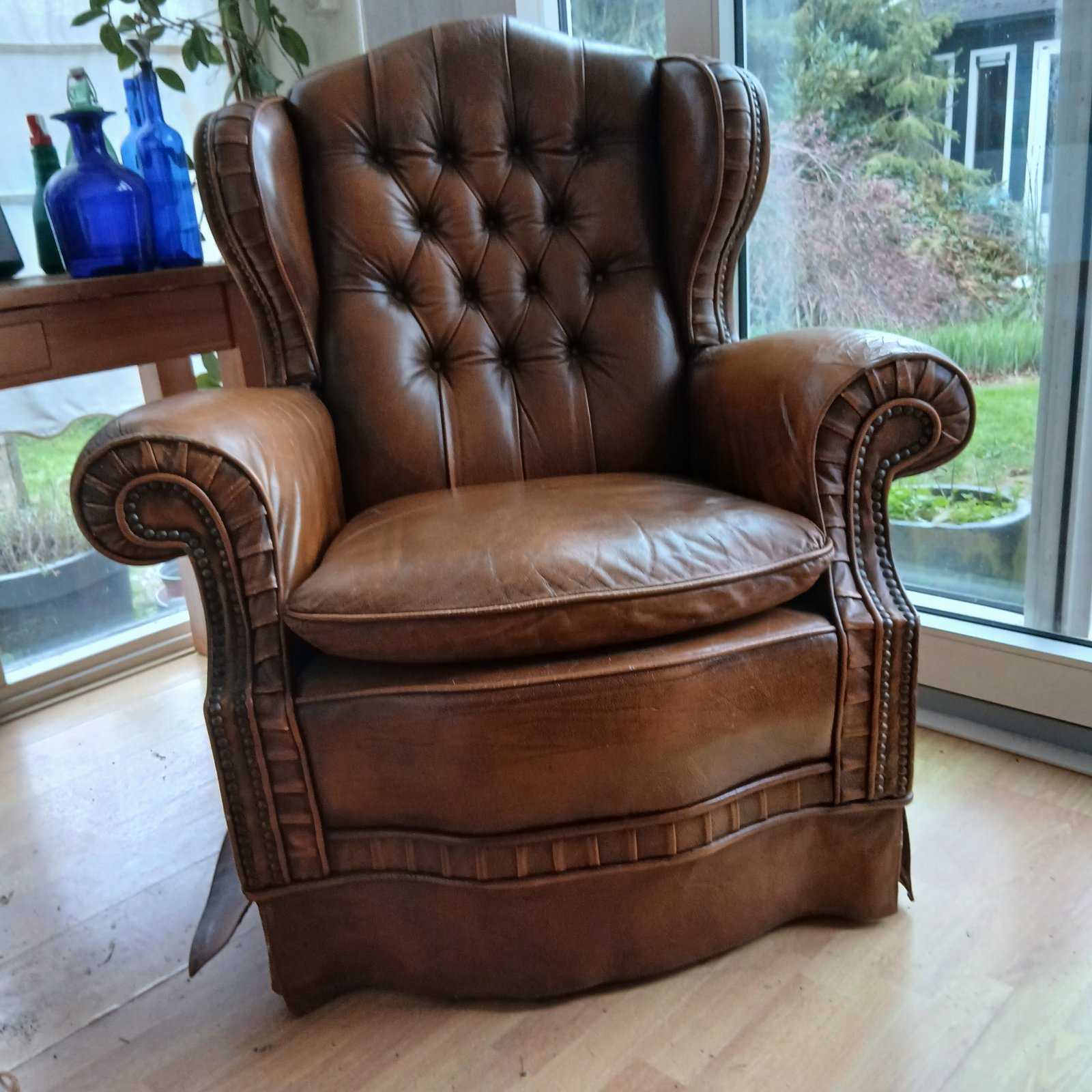 Vintage Dutch sheep leather wingback chair with tufted back and brass nailhead trim, showing wear on the armrests. - view 1
