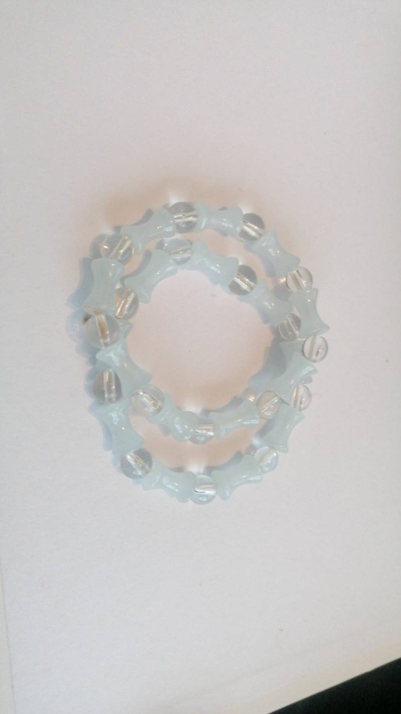 A contemporary beaded stretch bracelet made of clear faceted and pale blue hourglass-shaped beads.