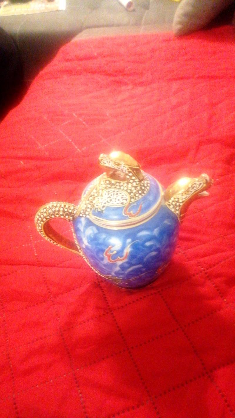 Chinese blue and white porcelain teapot with gilded dragon spout, handle, and lid finial on a red textile surface. - view 1