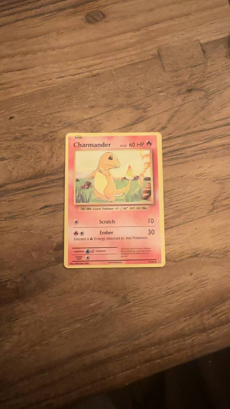 Wizards of the Coast Black Star Promo #9 Charmander non-holographic Pokémon trading card on a wooden surface.