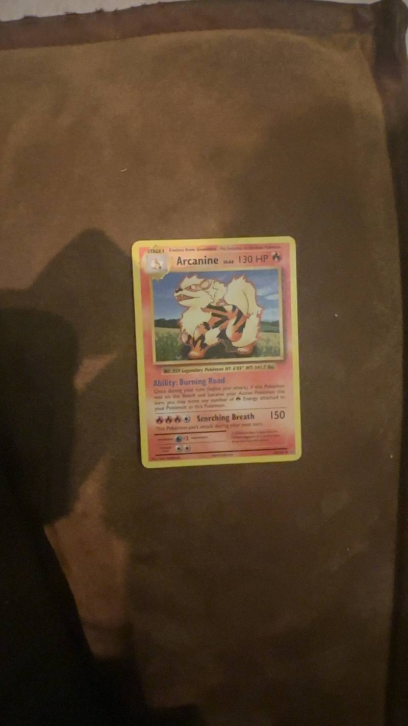 A holographic Arcanine Pokémon card from the XY Evolutions set, featuring classic Sugimori artwork on a brown surface.