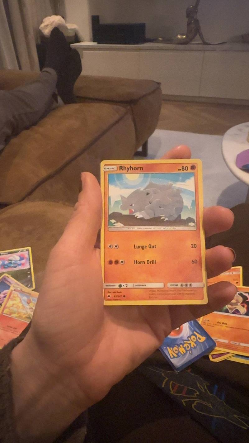 A close-up shot of a Rhyhorn Pokémon trading card from the Sun & Moon: Burning Shadows set, held in a hand. - view 1