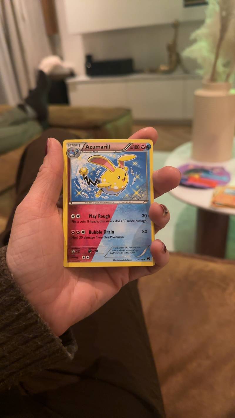 A shiny yellow Azumarill Pokémon card from the Steam Siege set being held in a hand.