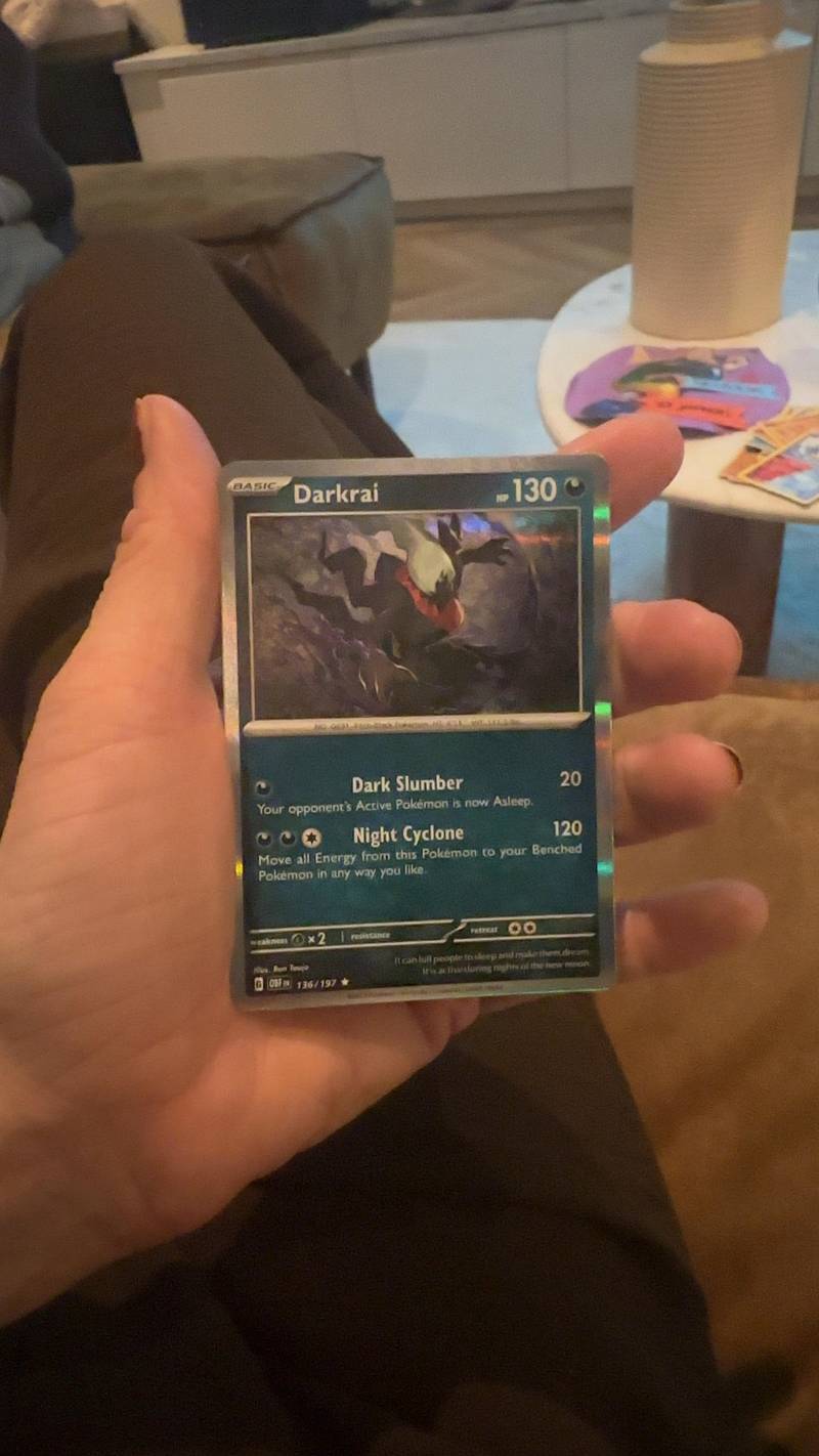 Close-up of a holographic English Pokémon TCG Darkrai card, number 136/197 from the Obsidian Flames set, held in a hand.