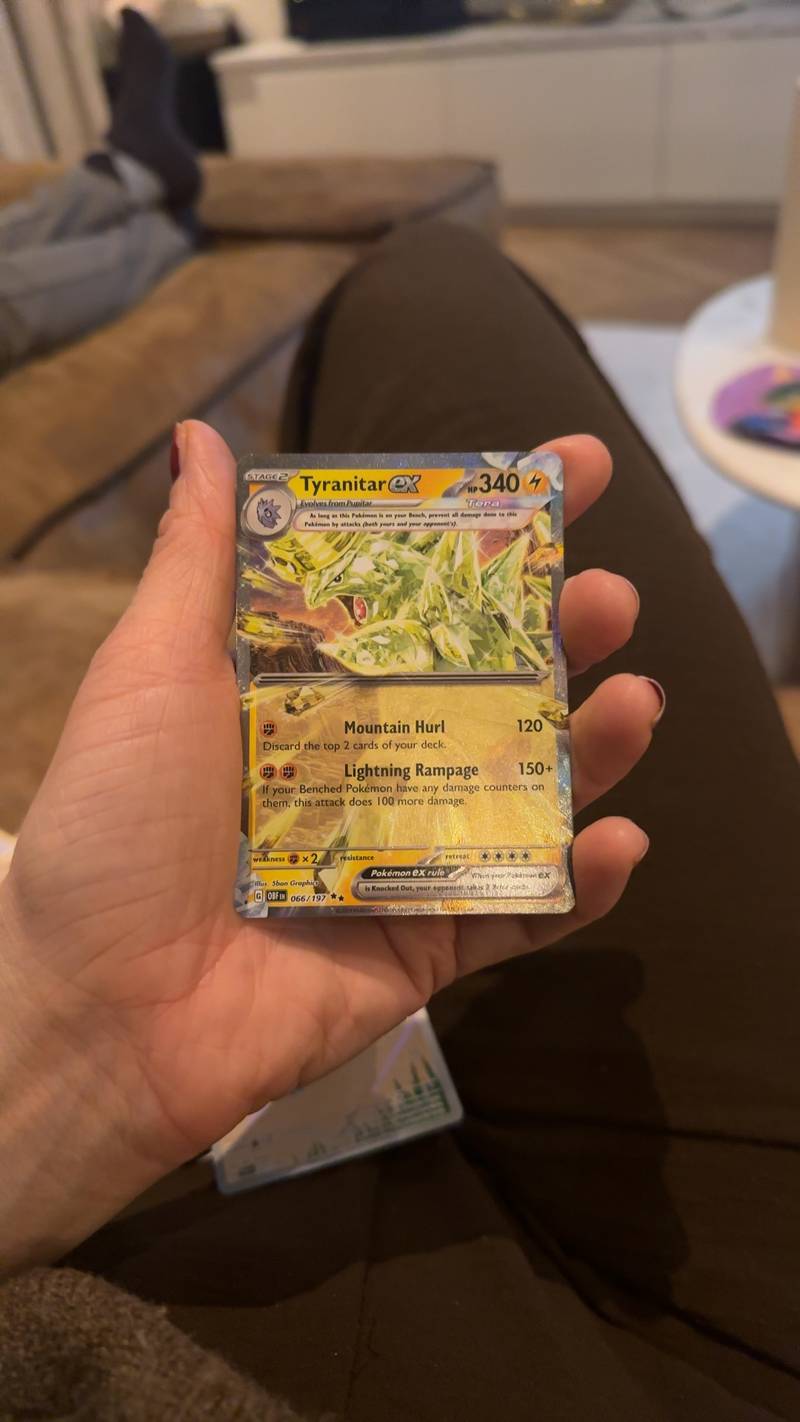 Pokémon TCG Tyranitar ex Tera card from Obsidian Flames, 066/197, held in hand, showing wear.