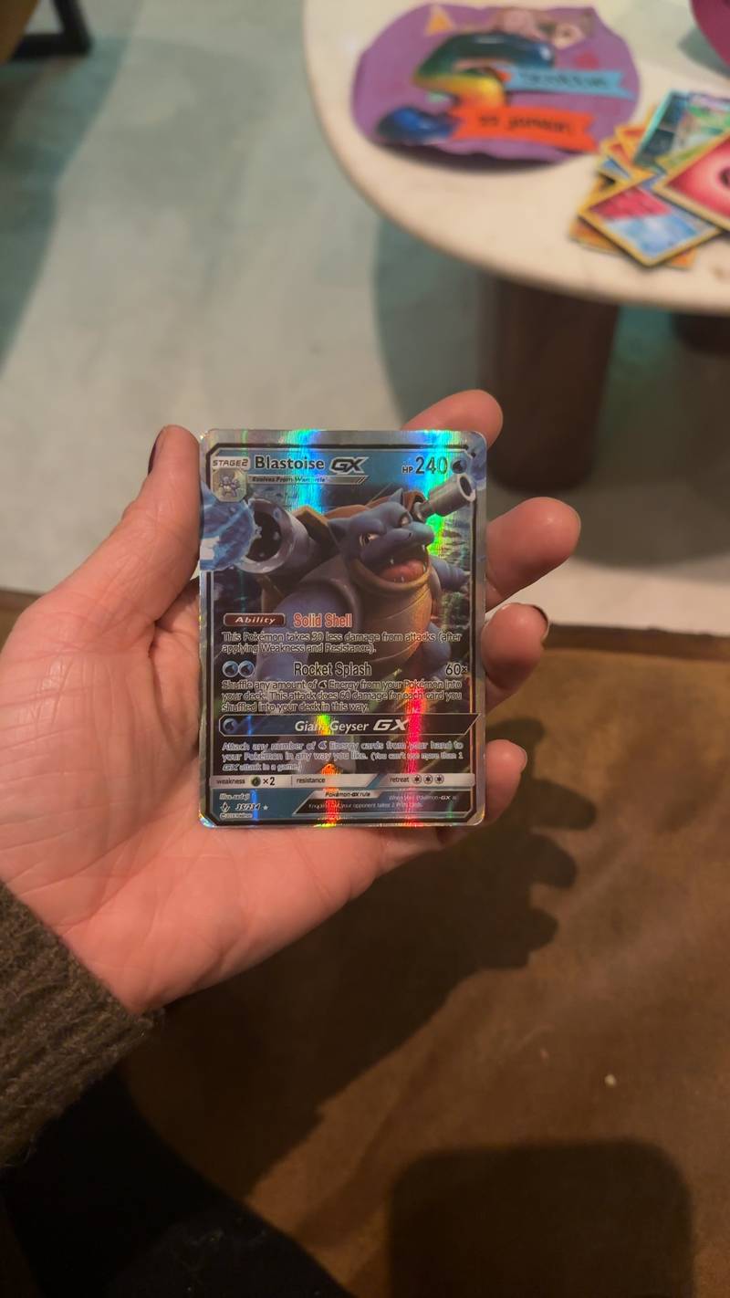 Full Art Blastoise GX Pokemon card from the Unbroken Bonds set, number 35/234, held in a hand showing textured holographic finish.