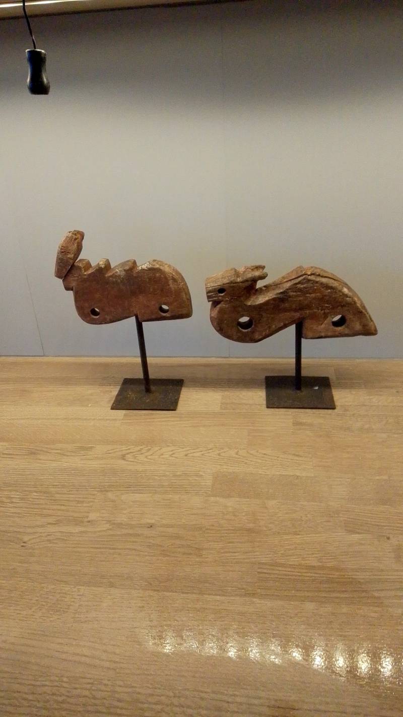 Pair of weathered, carved wooden architectural elements on metal stands, likely from Southeast Asia, showing traditional forms and aged patina. - view 1