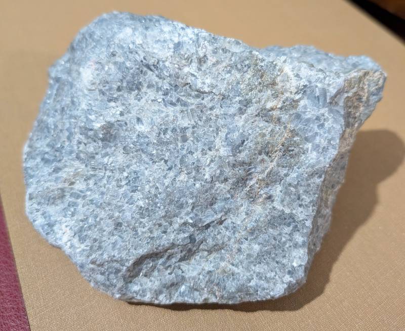 Rough mineral specimen of blue calcite, showing granular texture and pale blue color with some iron staining. - view 1