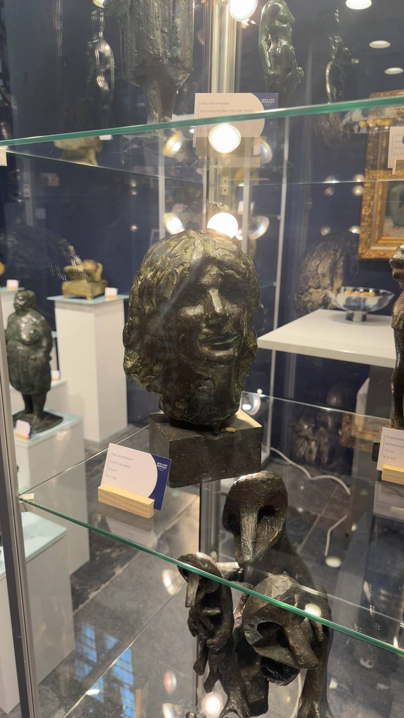Bronze portrait bust by Mari Andriessen on a stone pedestal inside a glass display case at Holland Heritage Gallery. - view 1
