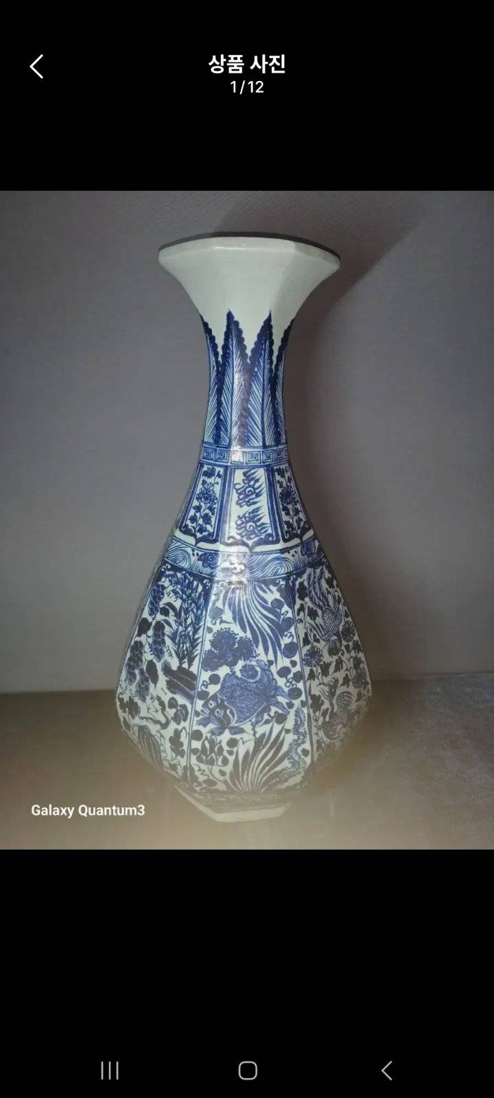A blue and white octagonal porcelain vase with fish and floral designs and a stained unglazed base. - view 1