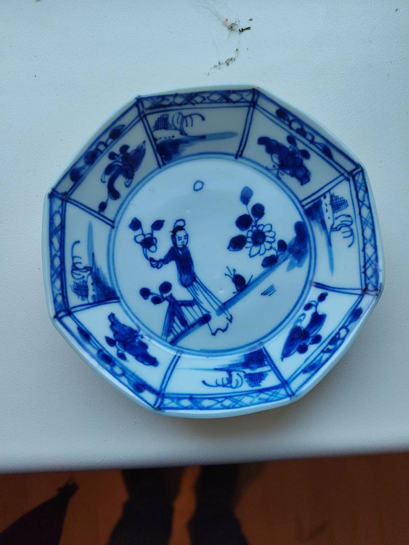 A small Chinese octagonal blue and white porcelain dish featuring a female figure in a garden and paneled landscape borders.