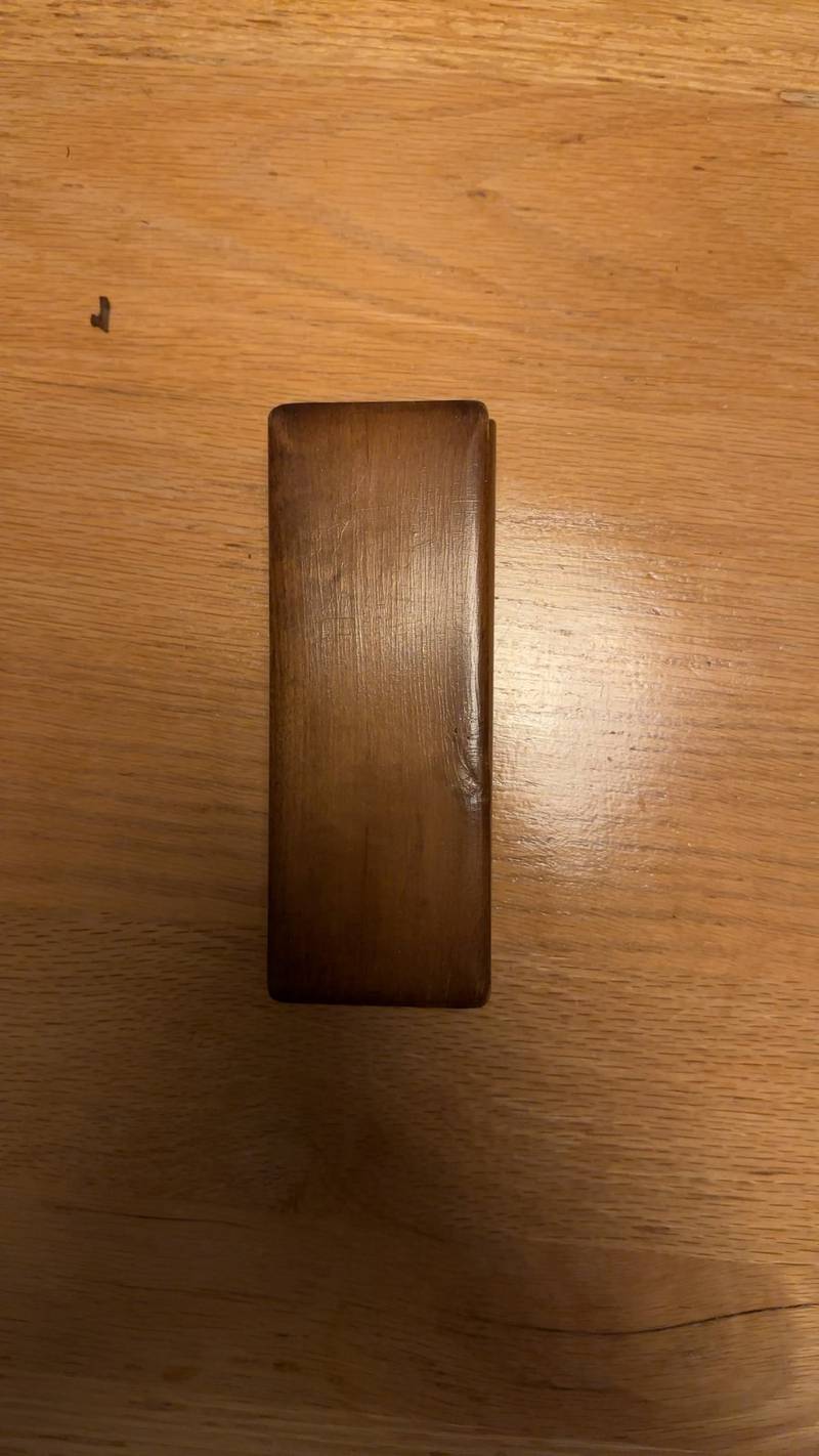 Small rectangular dark wood pen box with lid removed, showing a green felt-lined interior on a light oak table. - view 1