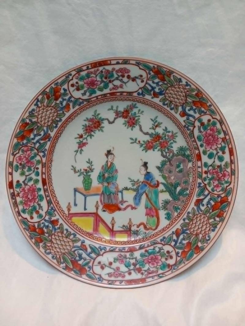 Chinese porcelain plate decorated with Famille Rose enamels depicting two figures in a garden setting, with a floral border. - view 1