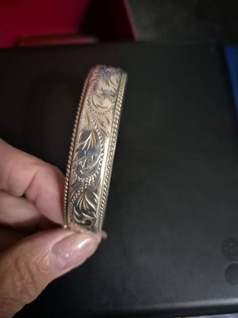 Silver-toned engraved bangle bracelet with floral patterns and twisted rope edges
